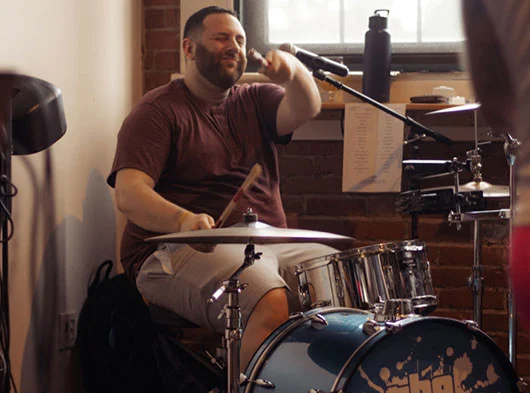 Joe Saad of Smoove Series pointing to the camera with a drumstick while playing at Two Roads Brewing in Stratford, CT